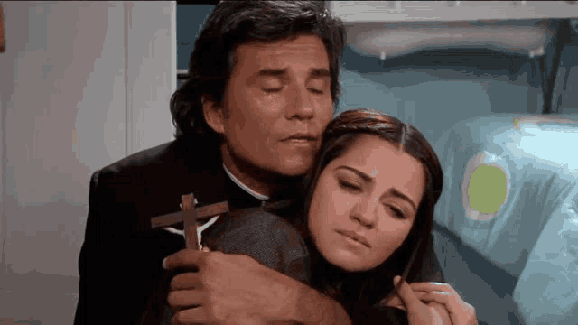a man is holding a cross while a woman looks on