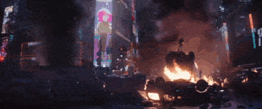 a person standing on top of a burning vehicle in a city