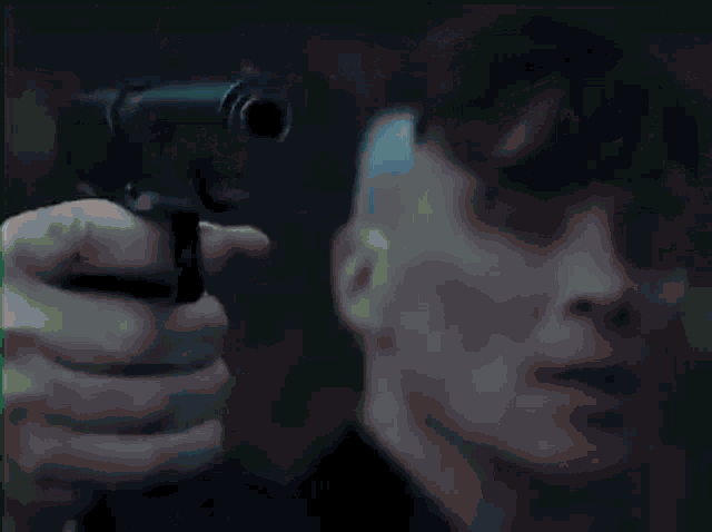 a man in a suit is standing in front of a window holding a gun .