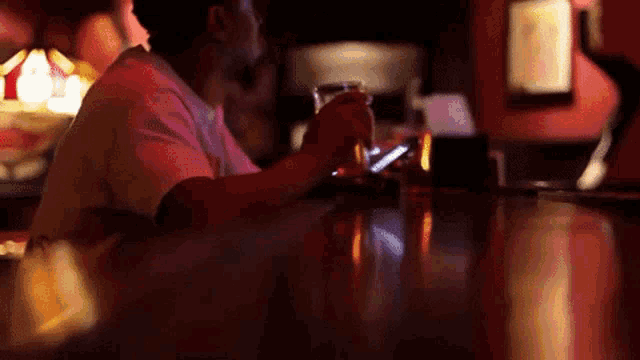 a man sitting at a bar looking at his cell phone