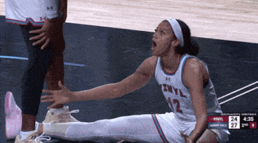 a female basketball player from vinyl sits on the floor during a game