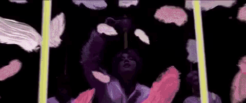 a man in a white shirt is holding a purple light in his hand in a dark room .