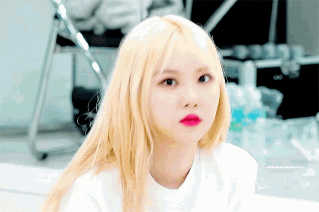 a girl with blonde hair and red lips is looking at the camera