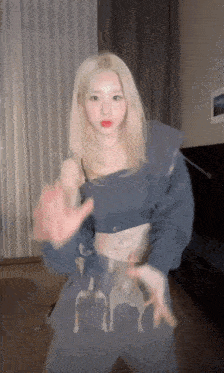 a blonde woman in a blue top is dancing in a room .