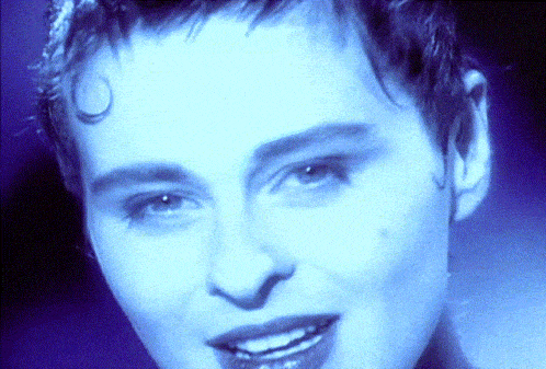 a close up of a woman 's face with a blue light behind her