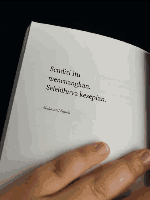 a person is holding a book with a quote by muhammad sapila on it