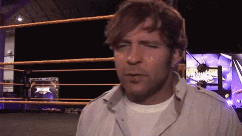 a man in a white shirt is standing in front of a wrestling ring that says nxt on it
