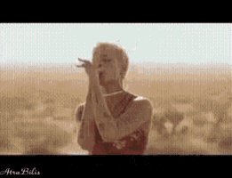 a woman in a red dress is blowing a kiss while standing in the desert