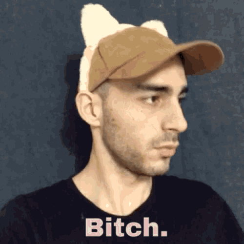 a man wearing a hat with cat ears and the word bitch on his shirt