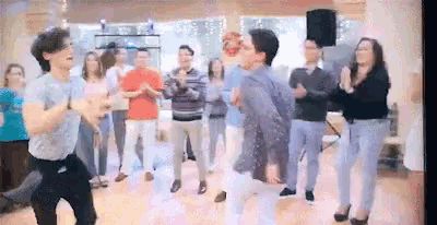a group of people are dancing in a room with a speaker .