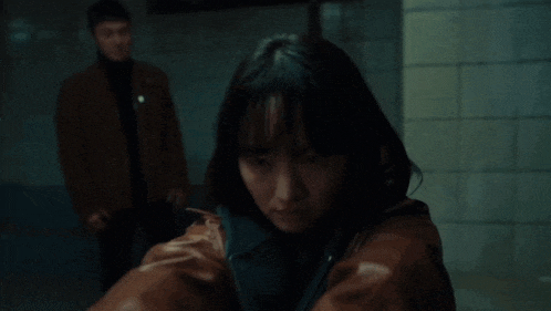 a woman is pointing a gun at a man in a dark room .