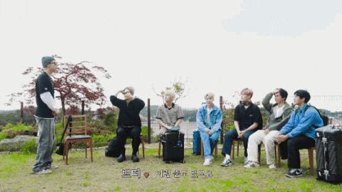 a group of people are sitting in chairs and a man is standing in the middle of the group