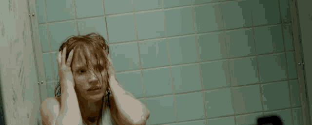 a woman with red hair is sitting in a bathroom with her hands on her head