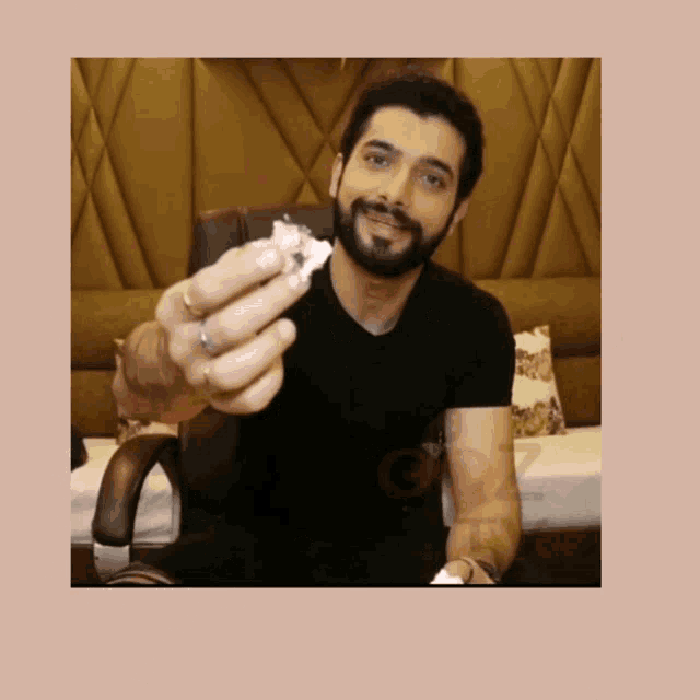a man in a black shirt is holding a piece of paper in his hand