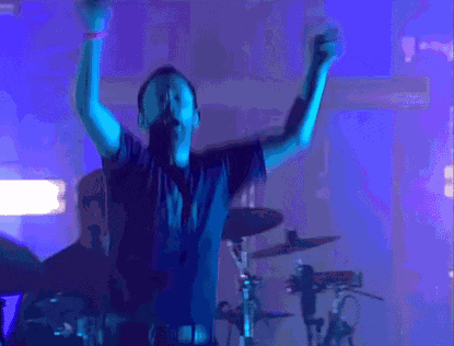 a man wearing a shirt that says atari holds his arms up in the air