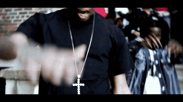 a man wearing a cross necklace is pointing at something