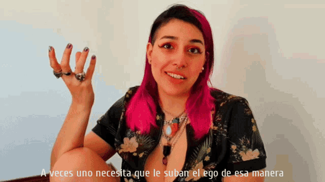a woman with pink hair is talking in spanish