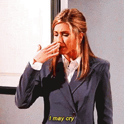a woman in a suit is covering her mouth with her hand and says i may cry