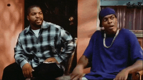 two men are sitting next to each other on a porch talking .