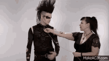 a woman is tying a man 's collar with a chain .