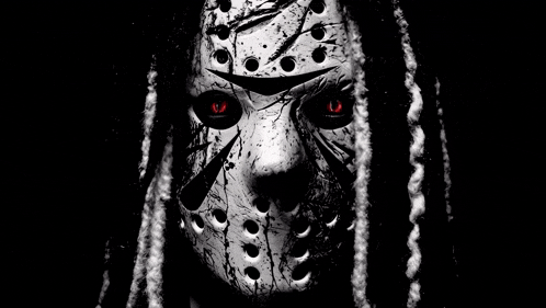 a black and white photo of a person wearing a jason voorhees mask with red eyes and dreadlocks .