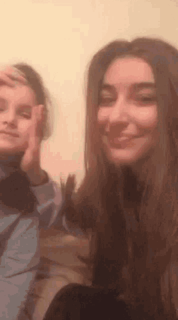 a boy and a girl are posing for a picture together . the girl is smiling and the boy is making a peace sign .