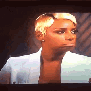 a woman with short blonde hair is making a funny face on a tv screen .