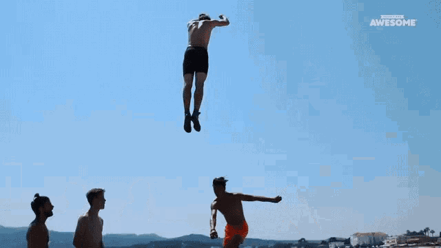 a group of men are standing on a beach and one of them is jumping in the air with the words awesome above him