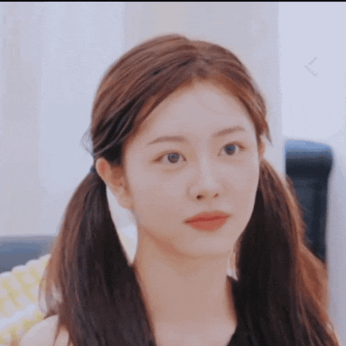 a girl with pigtails looks at the camera with a serious look on her face