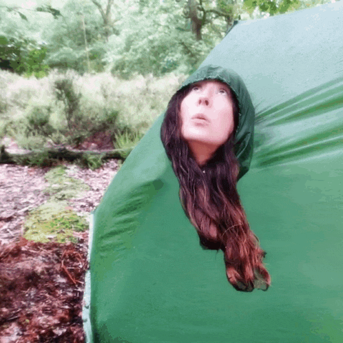 a woman in a green hooded jacket looks up into the sky