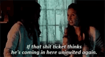 two women are standing next to each other in a dark room and one of them is talking to the other .