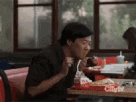 a man is sitting at a table in a restaurant eating food from a tray that says milk on it