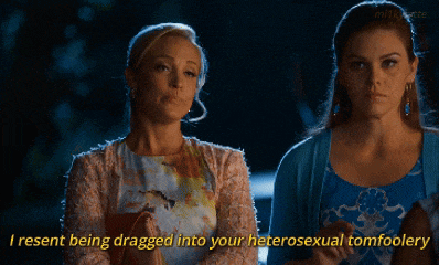 two women are sitting next to each other and one of them says " i resent being dragged into your heterosexual tomfoolery "