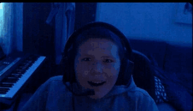 a young boy wearing headphones and a microphone looks at the camera