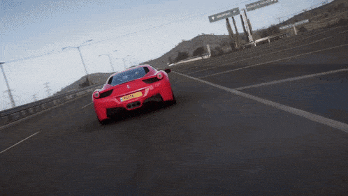 a red sports car is driving down a highway and has a license plate that says ' jc ' on it
