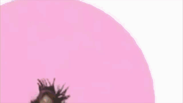 a woman is blowing a bubble with a giant pink balloon .