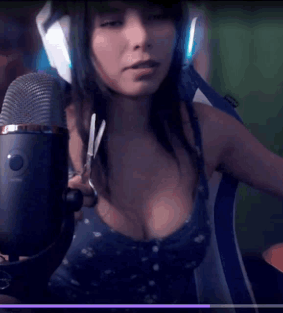 a woman is holding scissors in front of a microphone that says logitech on it