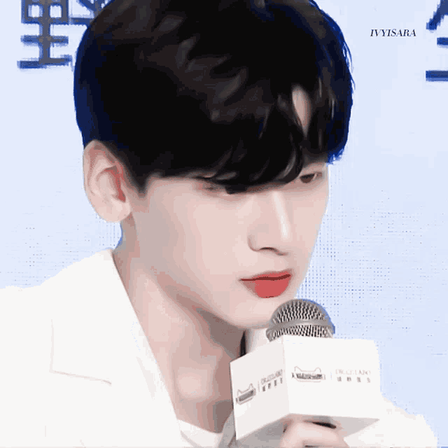a close up of a person holding a microphone with ivyisara written on the bottom right