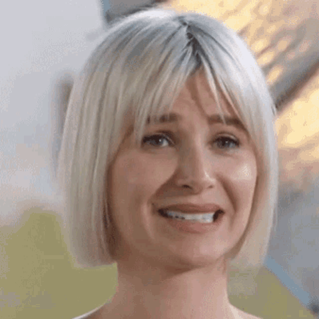 a close up of a woman 's face with blonde hair and bangs .