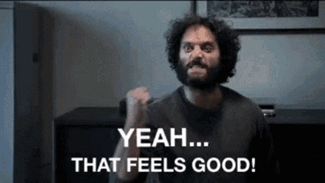 a man with a beard is making a fist and says yeah that feels good