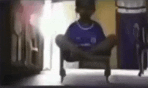a person is sitting on a chair with their legs crossed in a dark room .