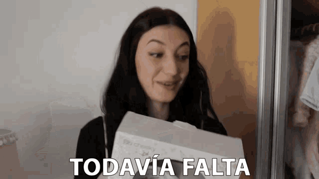 a woman holding a box with the words todavia falta written on it