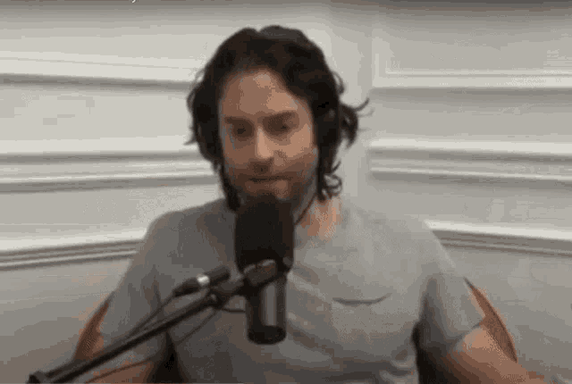 a man is sitting in front of a microphone while wearing headphones .