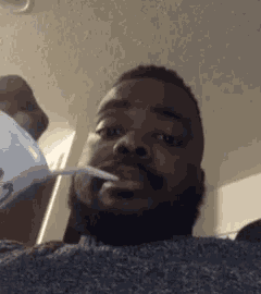 a man with a beard is drinking from a plastic cup .