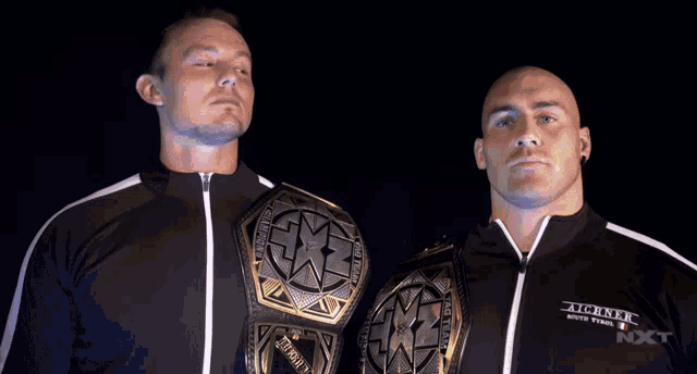 two men are standing next to each other and one of them is wearing a jacket that says axx