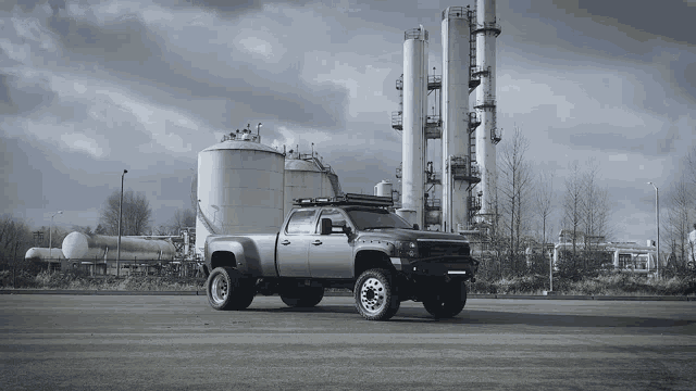 a silver truck is parked in front of a large factory