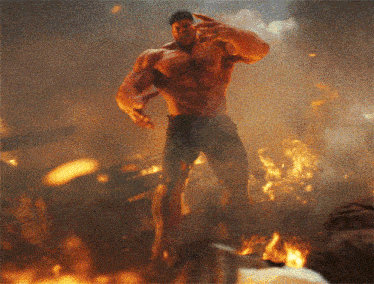 a man is standing in front of a fire and giving a thumbs up
