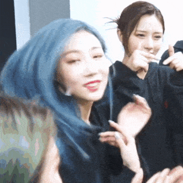 a woman with blue hair is standing next to another woman with brown hair .