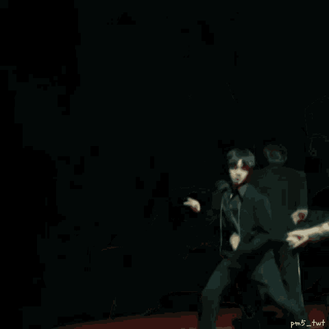 a man in a black suit is dancing on a red carpet while another man looks on .
