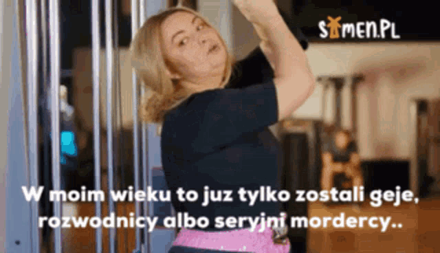 a woman is standing in front of a sign that says " w moim wieku to już tylko zostałi geje "